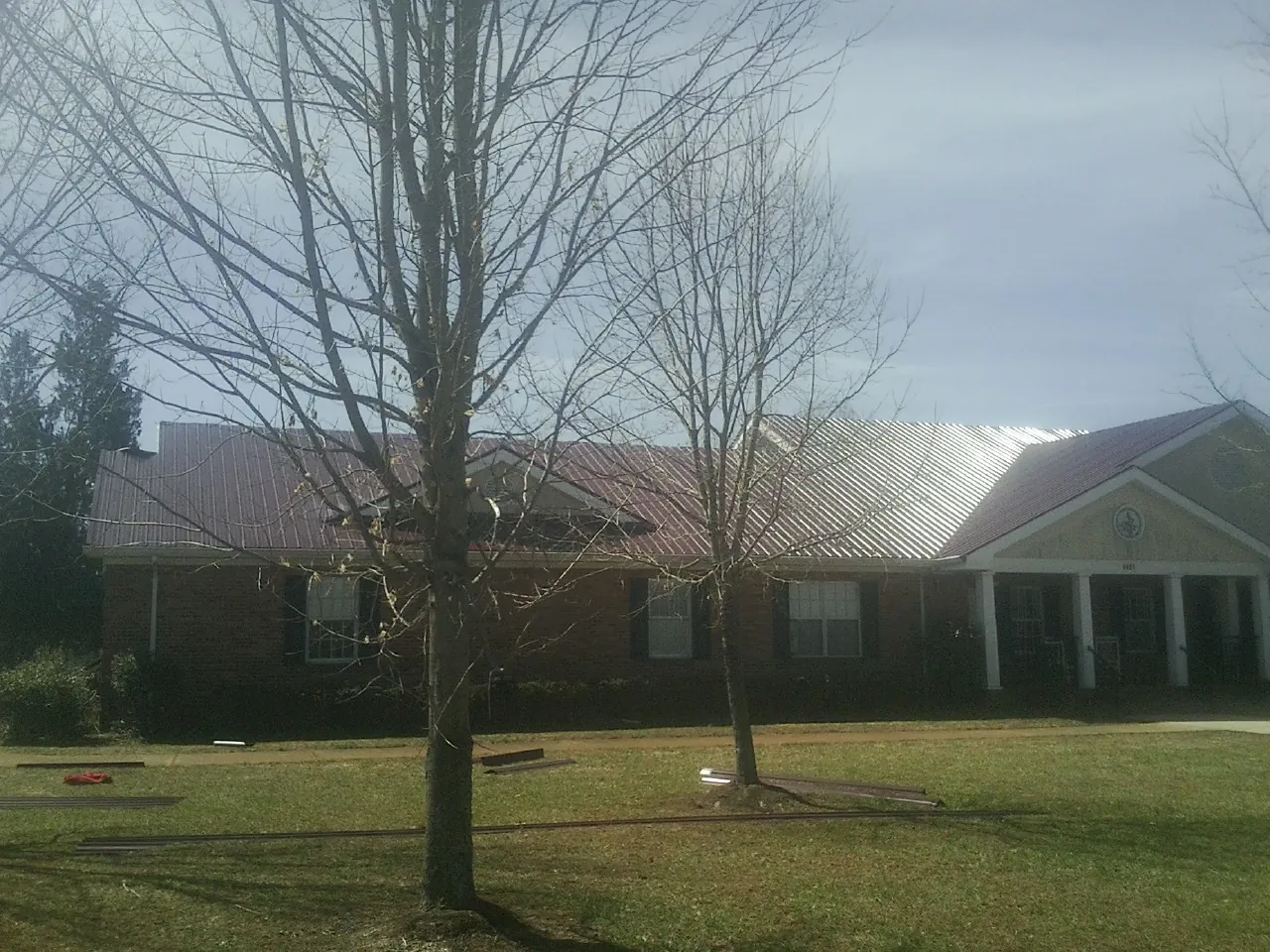 Red metal roof on a brick building seen from the front lawn in Tama
