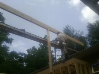 Carpenter setting a ridge beam over a new addition frame — Ice Dam Removal by Roofing Brothers in Tama