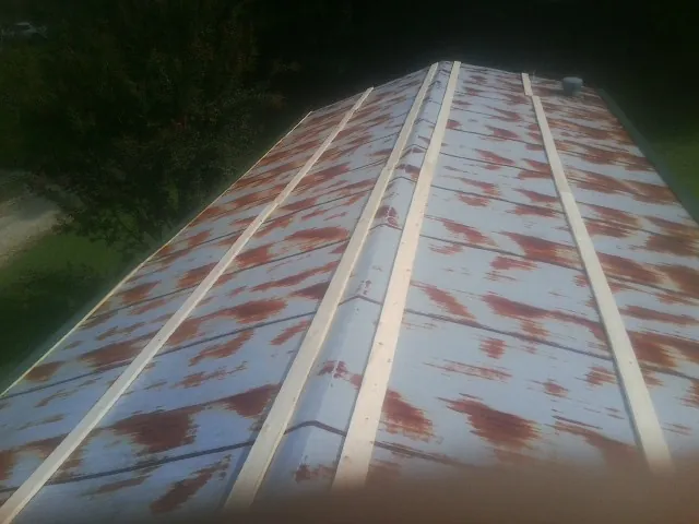 Rusted metal roof panels with new wood purlins before replacement — Storm Damage Roof Repair in Tama by Roofing Brothers