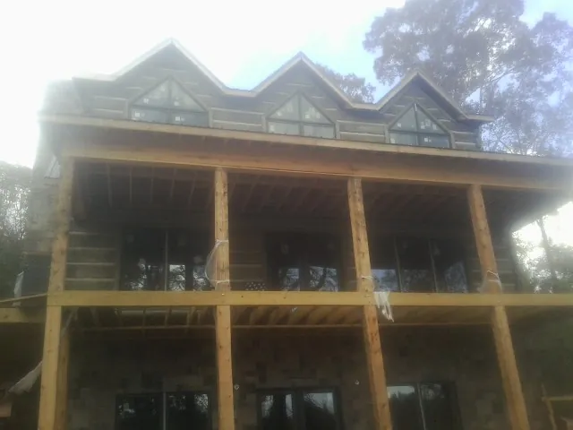 Dormers and porch framing on a large log home under construction — Roof Coating work by our crew in Tama