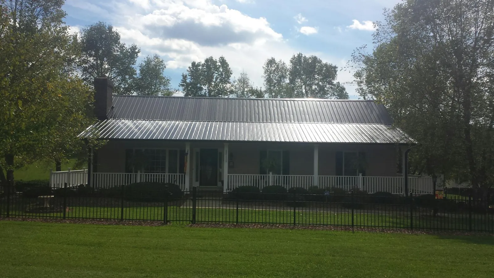 Gray metal roof on a brick ranch with a full width front porch — Gutter Guard Installation work by our crew in Tama