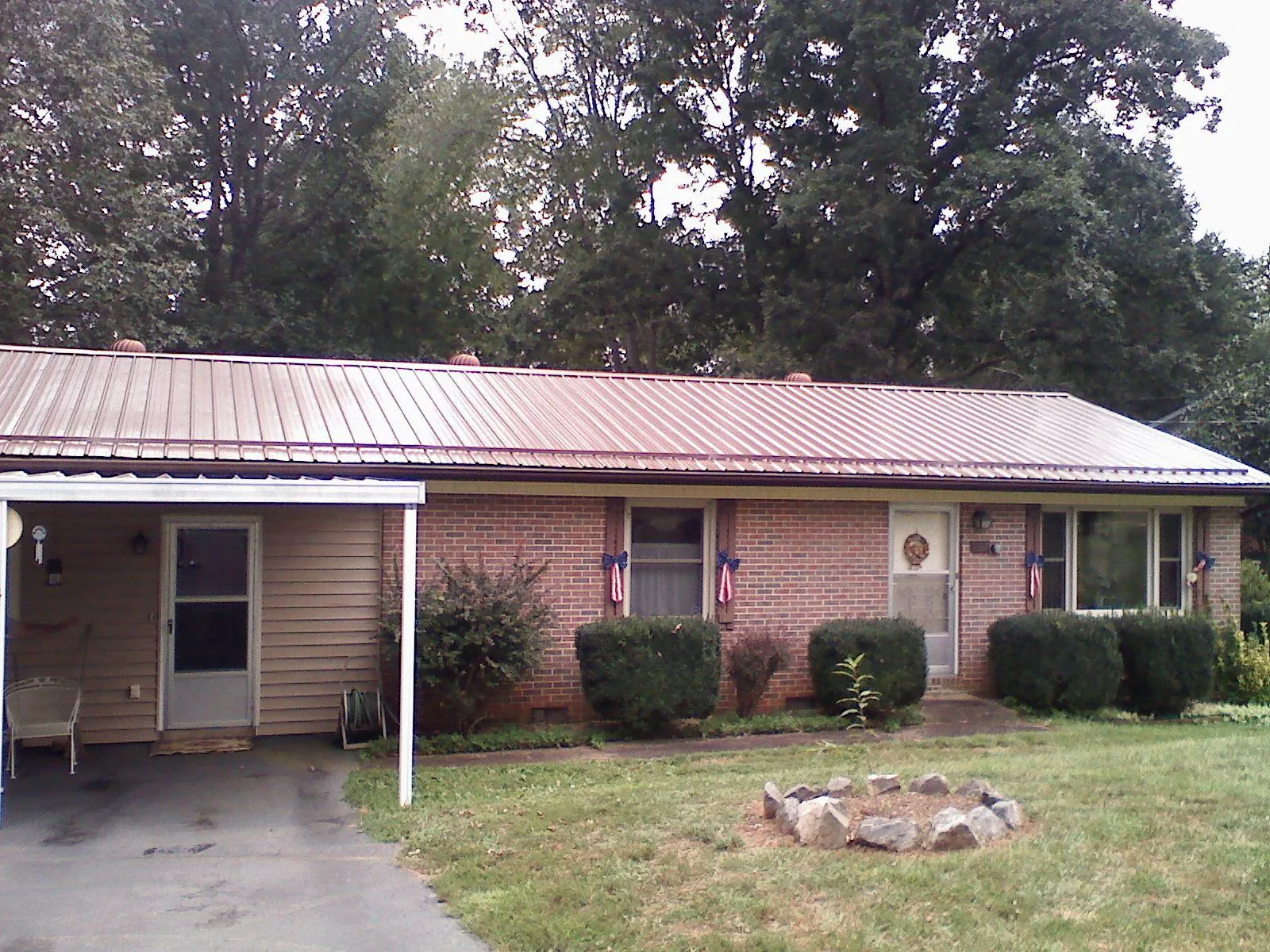 Bronze metal roof and carport on a brick ranch home — Roof Repair work by our crew in Tama